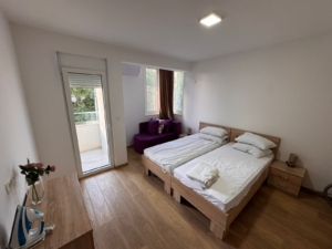 Elegant Ulcinj bedroom with twin beds, purple sofa, balcony & lush views. Prime real estate by Ekosphere on montenegro-listings.me.