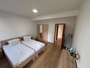 Discover a stylish Ulcinj bedroom with twin beds, mirrored wardrobe, dresser, and ironing board—prime real estate by Ekosphere DOO.