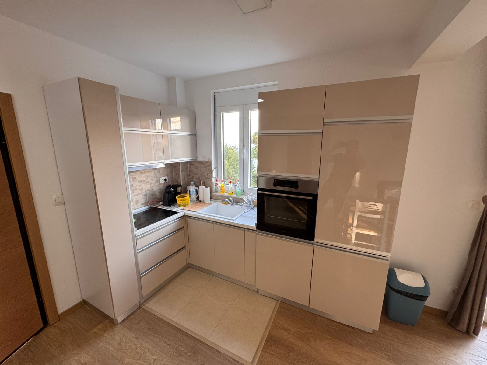 Stylish modern kitchen in Ulcinj with beige cabinets, built-in oven, and wooden flooring&mdash;exclusive on montenegro-listings.me by ekosphere doo.