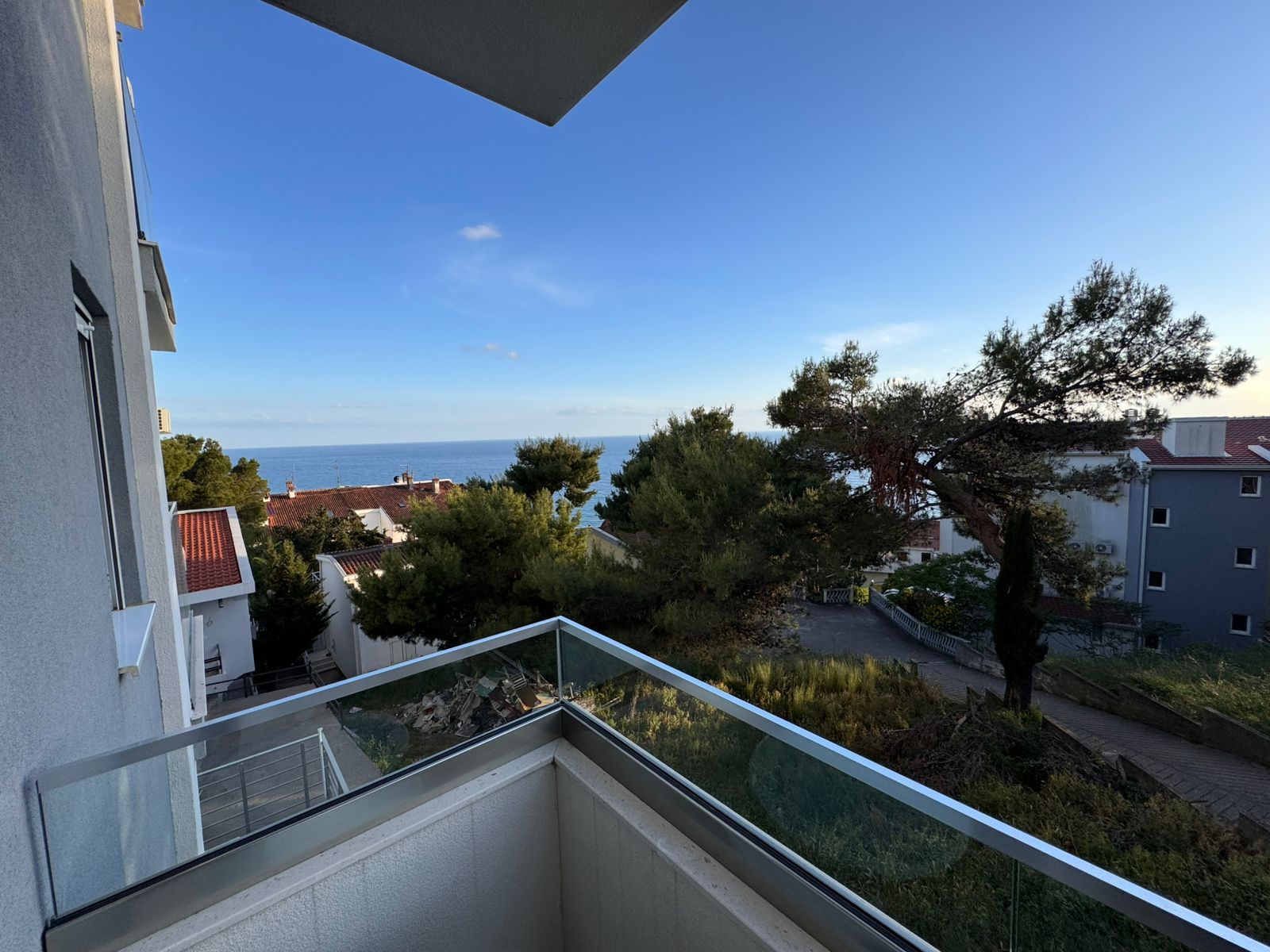 Stunning glass-railed balcony view over sea, rooftops, and greenery&mdash;prime Ulcinj Montenegro property at montenegro-listings.me by Ekosphere doo.