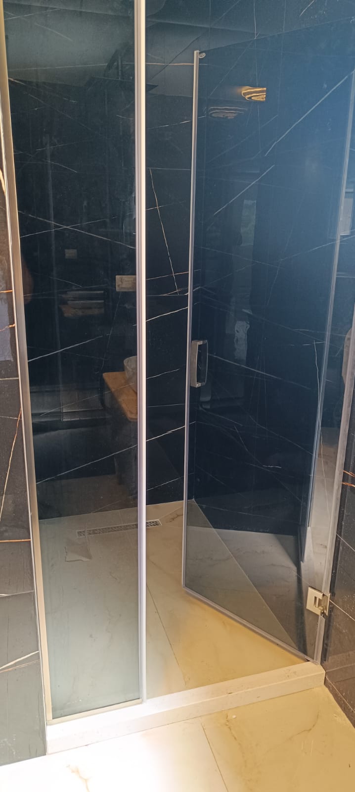Luxurious shower with marble-patterned tiles, glass panels, and wood accents&mdash;exclusive property in Ulcinj by ekosphere doo on montenegro-listings.me.