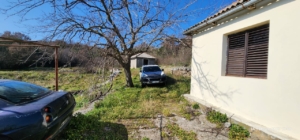 Charming Ulcinj property with parking, brown shutters, sunlit lawn, and shed—prime investment on montenegro-listings.me by ekosphere doo.