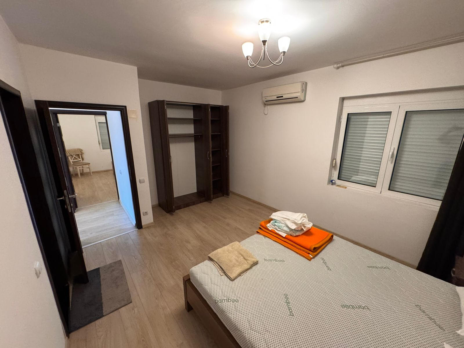 Modern Ulcinj bedroom with wood floors, open wardrobe, AC, double windows—exclusive on montenegro-listings.me by Ekosphere doo.
