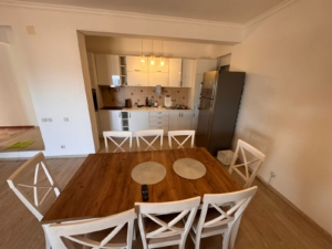 Modern Ulcinj kitchen with white cabinets, stainless fridge, wood table; ideal real estate on montenegro-listings.me by ekosphere doo.