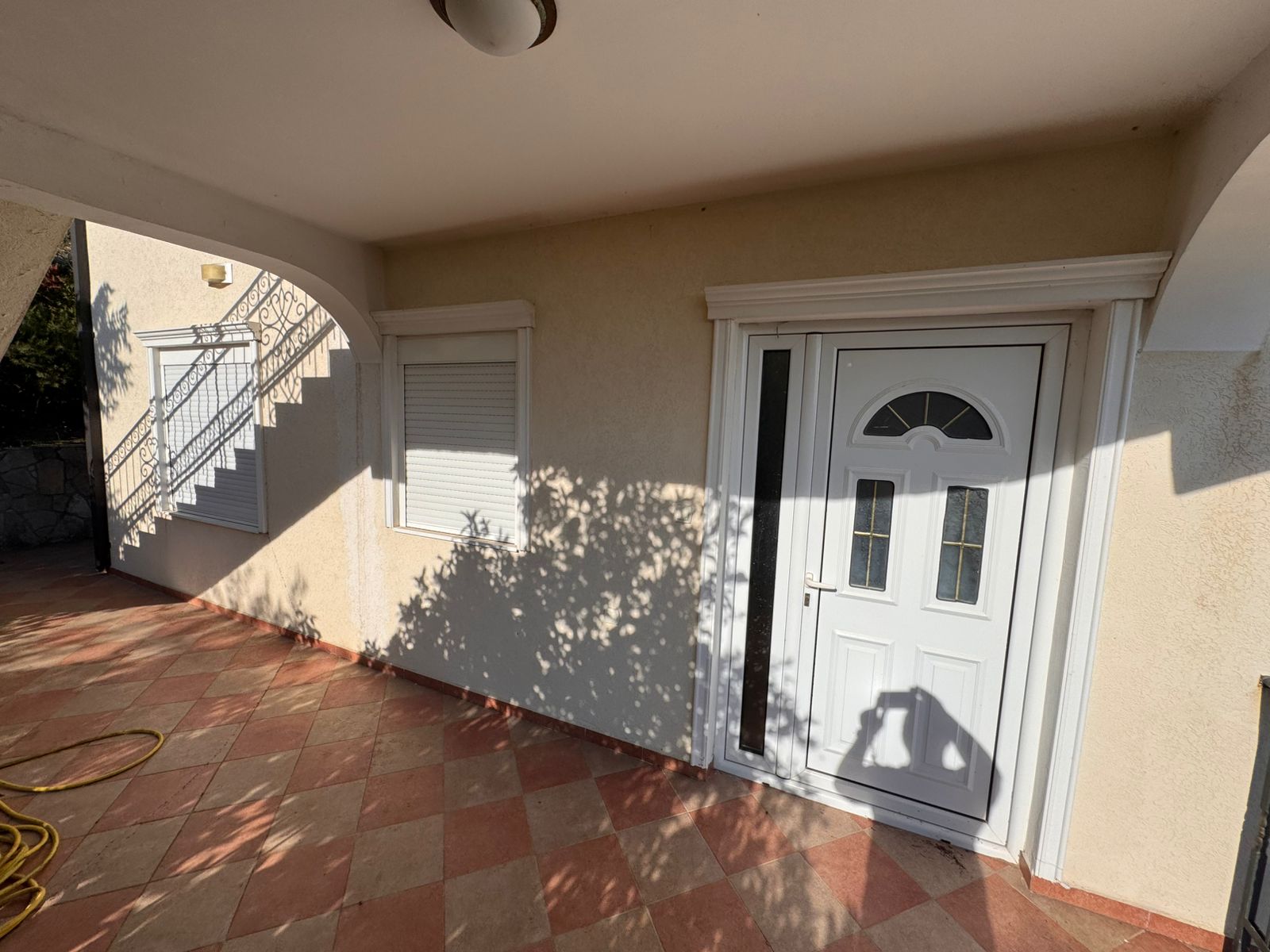 Modern white front door with glass panel and tiled entry, ideal Ulcinj real estate by ekosphere doo via montenegro-listings.me.