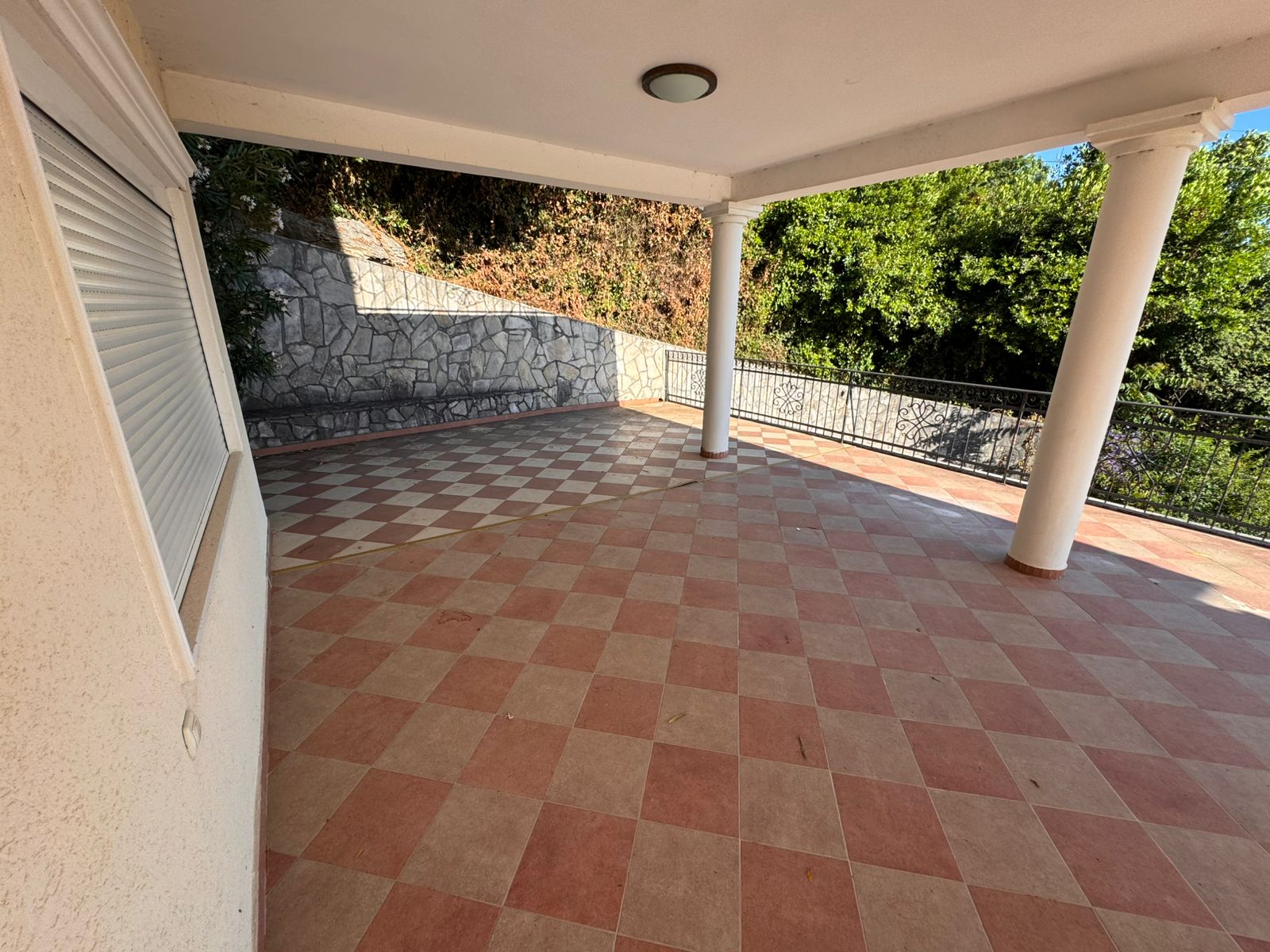 Elegant covered patio in Ulcinj, Montenegro with checkered tile, white columns, and lush greenery. Exclusive by montenegro-listings.me (Ekosphere).