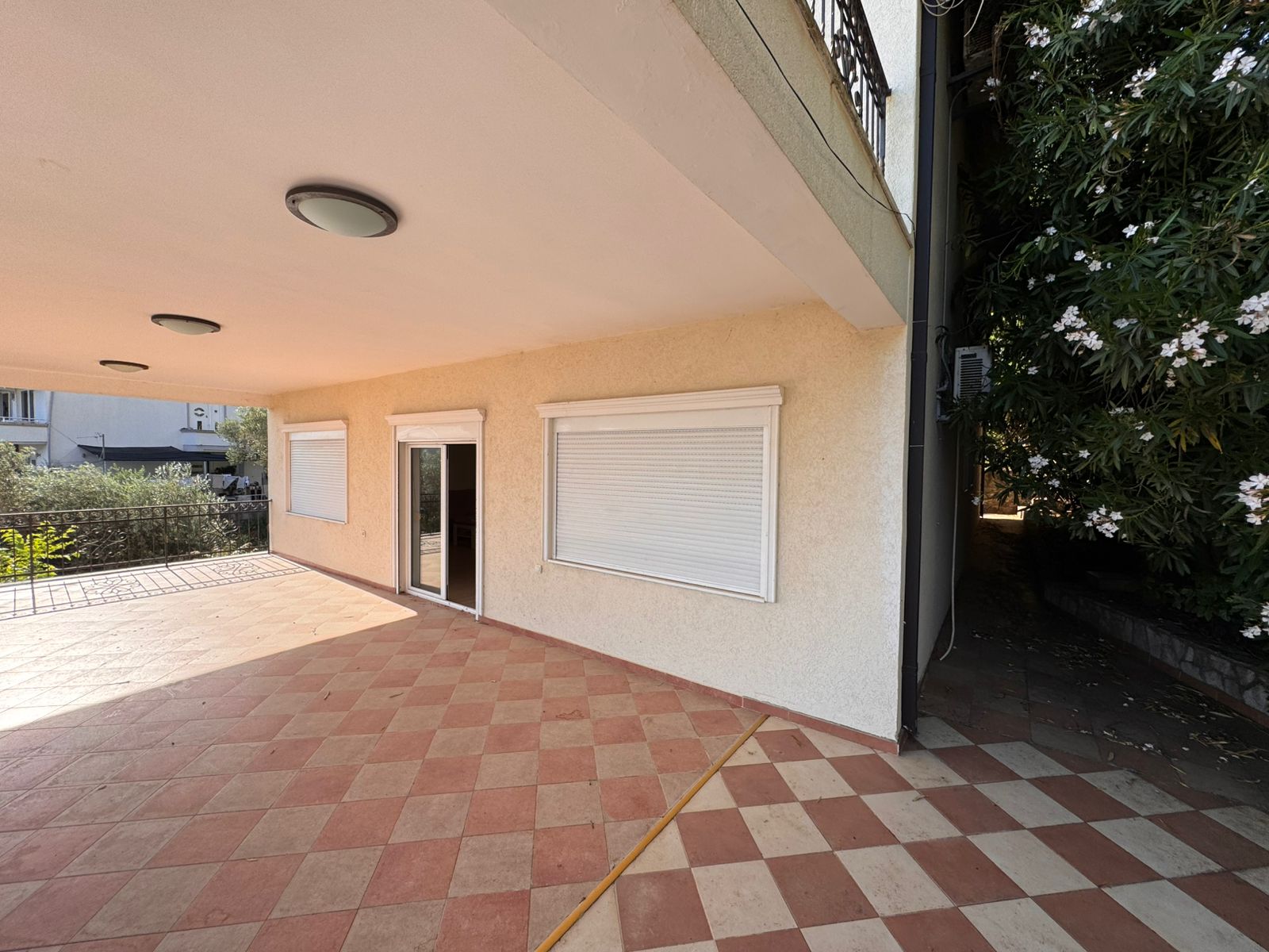 Stylish covered patio with checkered tile floor, white shutters, and glass door&mdash;top Ulcinj real estate at montenegro-listings.me by Ekosphere doo.