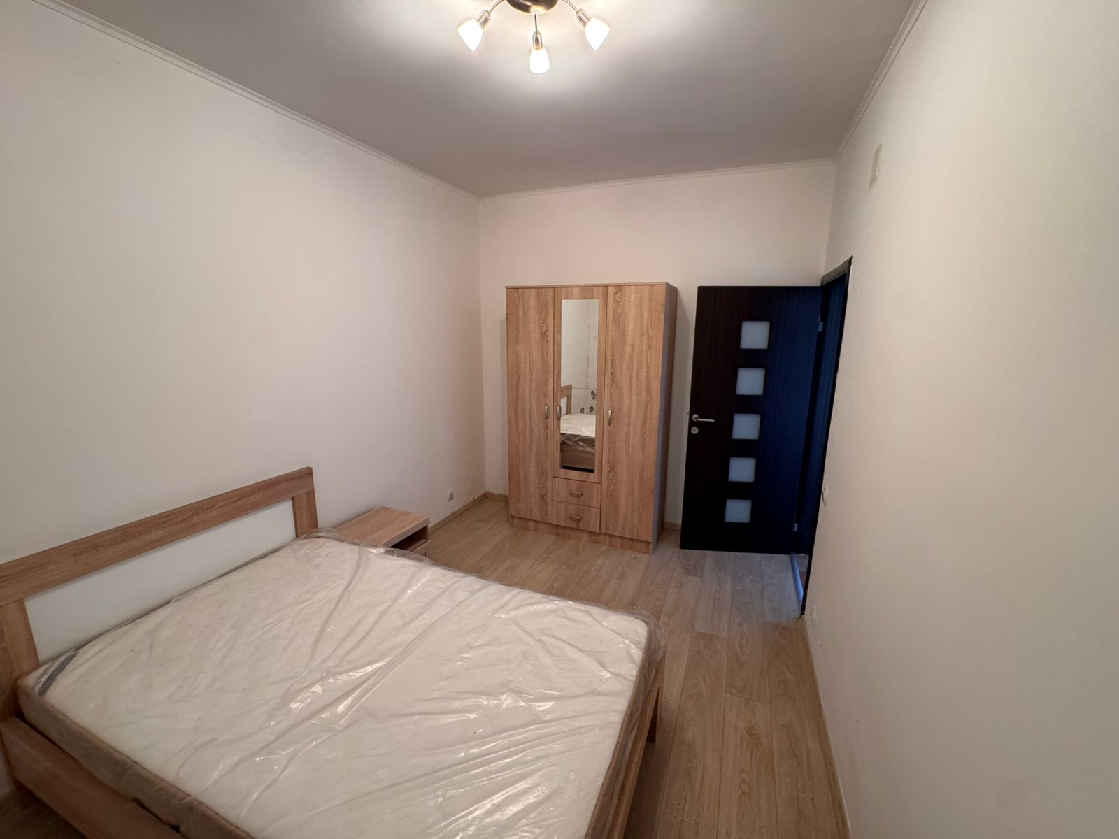 Modern Ulcinj bedroom with wooden bed, mirrored wardrobe, and sleek flooring&mdash;prime investment at montenegro-listings.me by Ekosphere DOO.