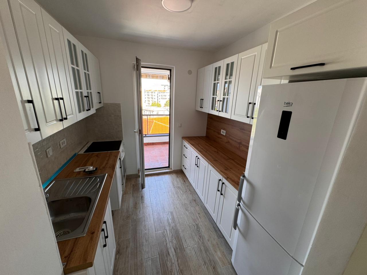 Modern Ulcinj kitchen with white cabinets, wood counters, balcony access; premium investment on montenegro-listings.me by Ekosphere.