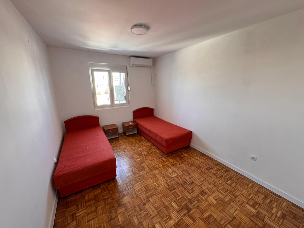 Cozy Ulcinj room with parquet floors, air conditioning, twin beds, and natural light—ideal real estate at montenegro-listings.me.