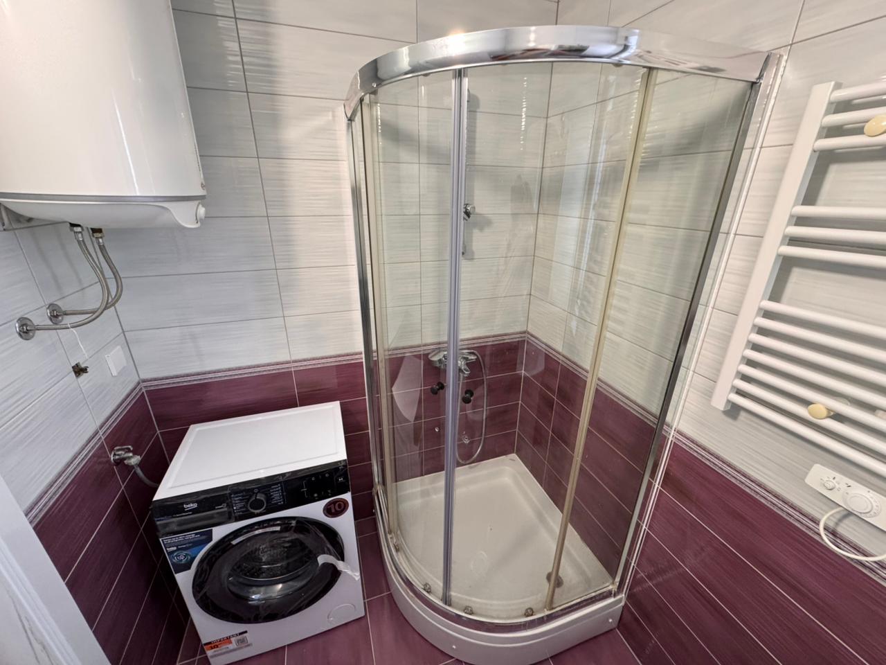 Modern Ulcinj bathroom with shower, washing machine, and chic tiles—invest in Montenegro real estate via montenegro-listings.me by Ekosphere doo.