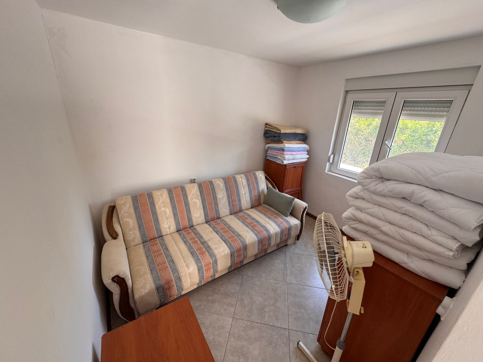 Discover a cozy, meticulously maintained Ulcinj property featuring a stylish striped sofa, desk, and storage; invest with montenegro-listings.me by ekosphere doo.