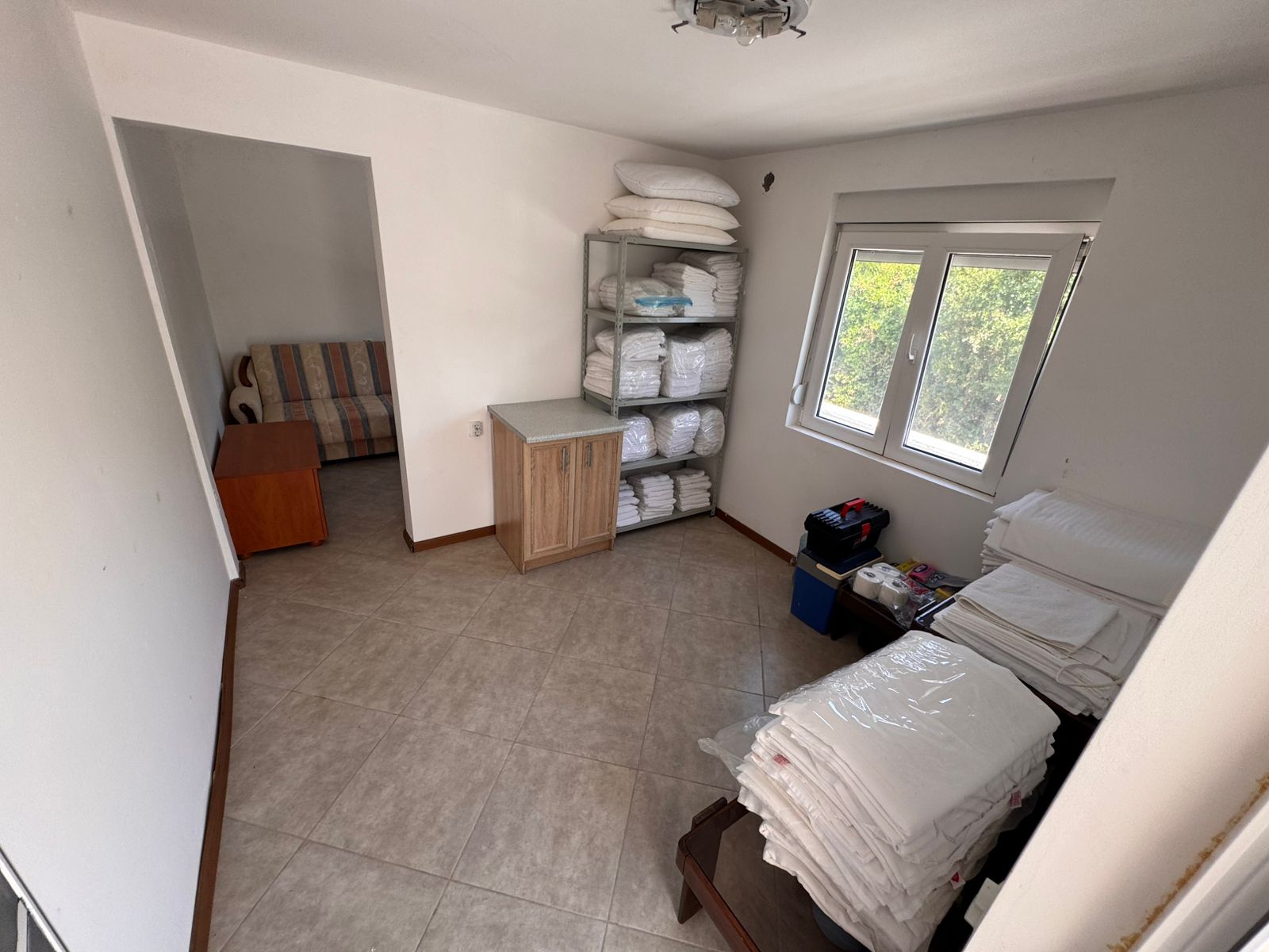 Modern tiled utility room in Ulcinj, Montenegro with organized storage, natural light, and adjoining lounge—exclusive at montenegro-listings.me by ekosphere doo.