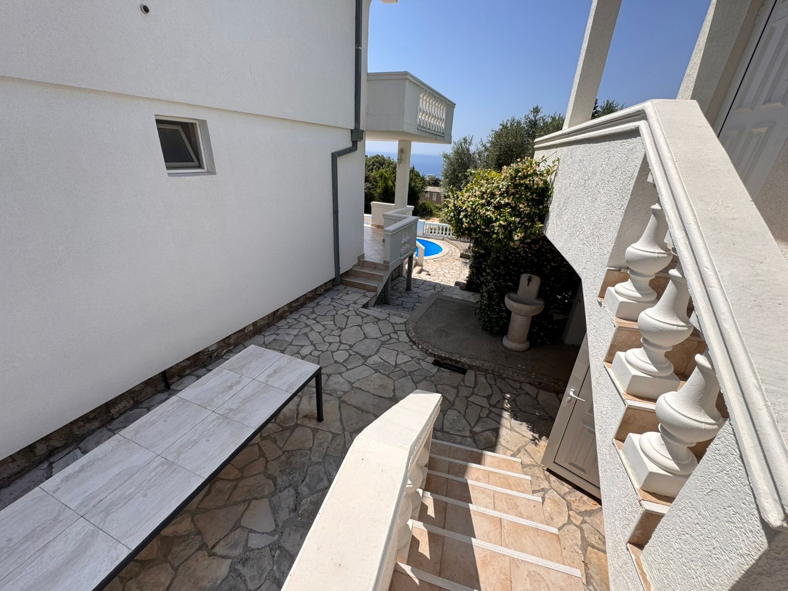 Elegant stone steps and walkway lead to a sunny tiled patio and pool&mdash;prime Ulcinj real estate with montenegro-listings.me by Ekosphere.