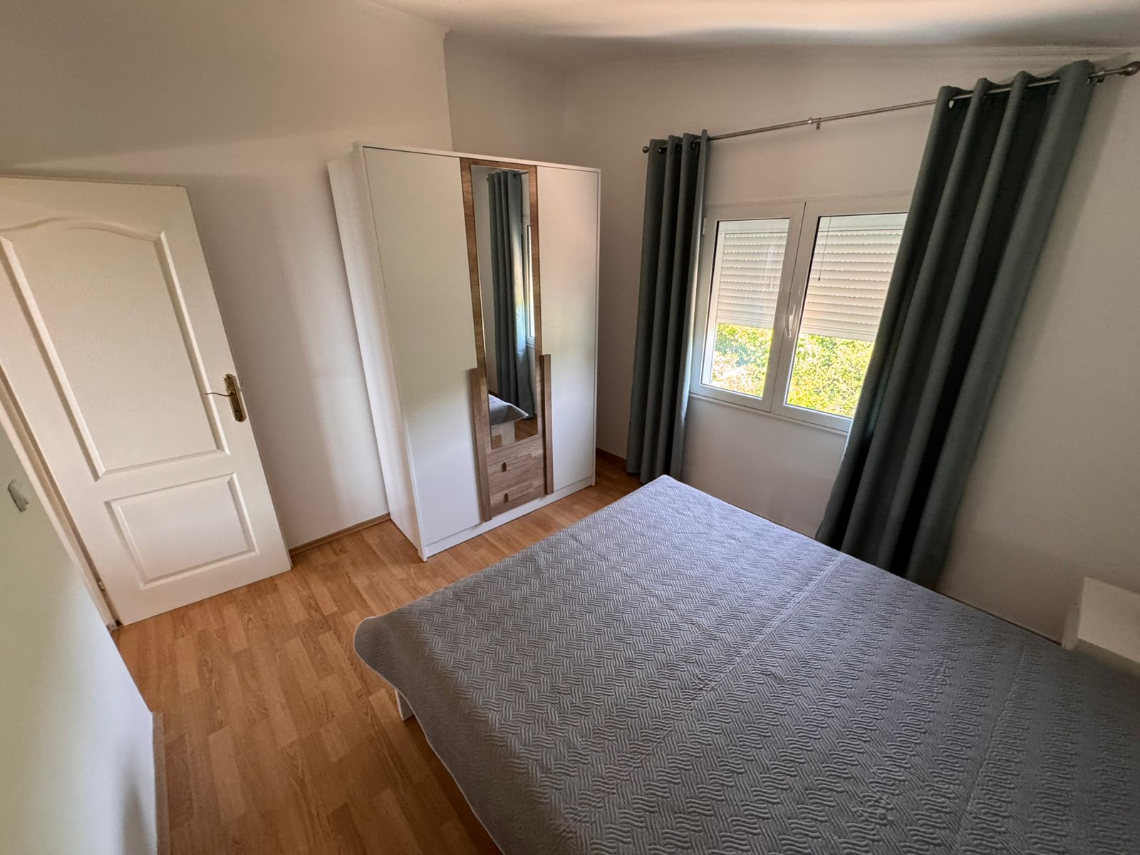 Stylish Ulcinj bedroom: wooden flooring, gray bed, mirrored wardrobe. Invest in prime Montenegro real estate by Ekosphere on montenegro-listings.me.