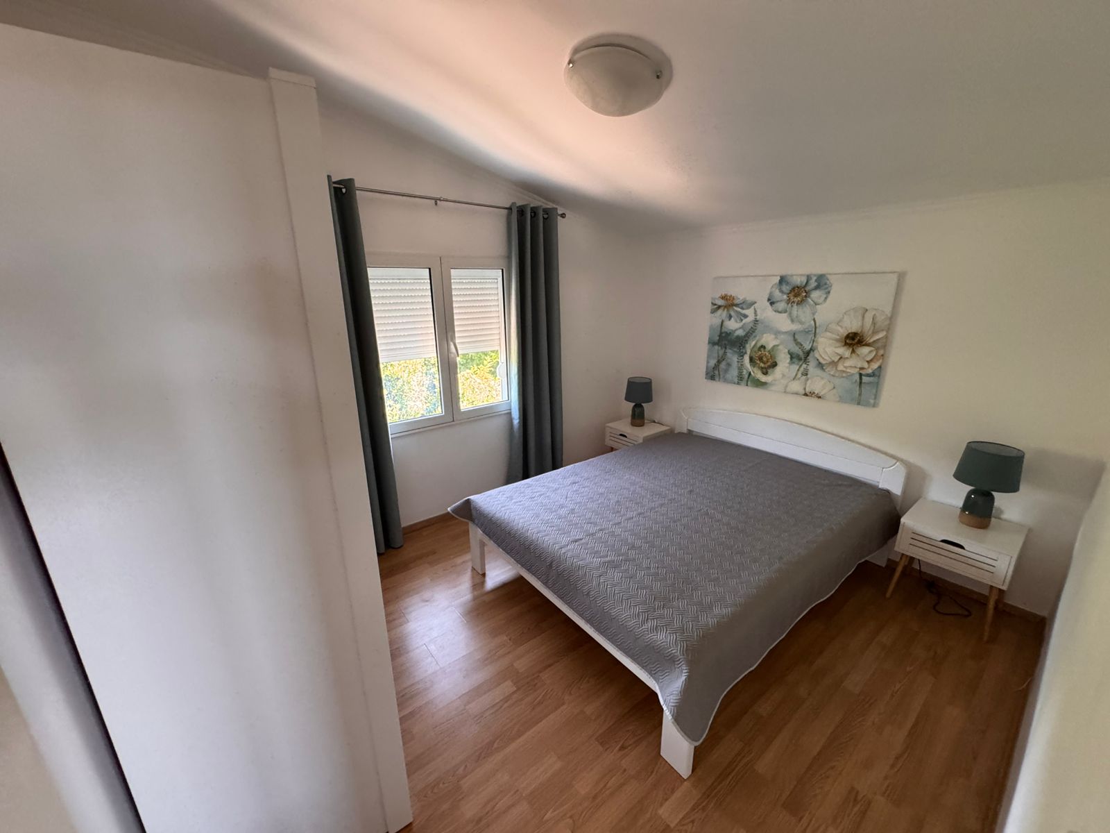 Elegant Ulcinj bedroom with hardwood floors, stylish bed, blue lamps; prime real estate&mdash;exclusively on montenegro-listings.me by ekosphere doo.