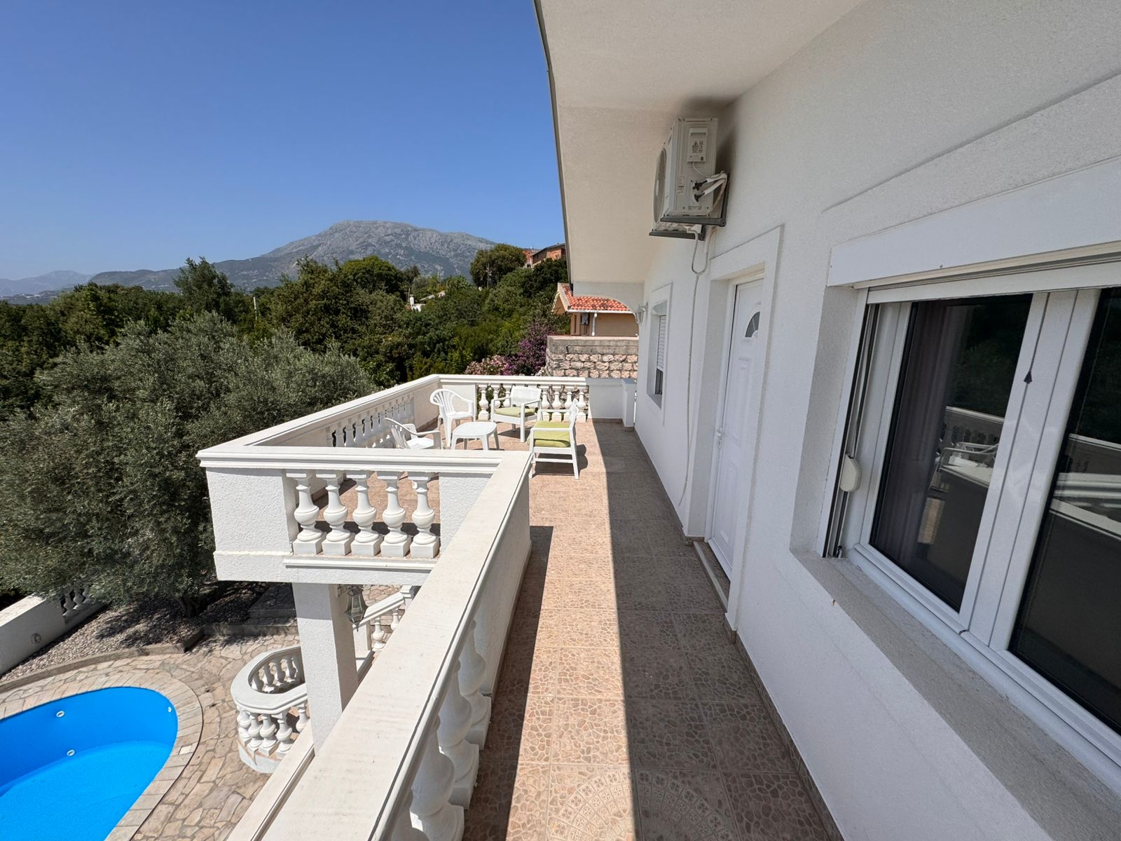 Elegant white balcony with tiled floor, pool view, scenic mountains&mdash;prime Ulcinj real estate by Ekosphere DOO at montenegro-listings.me.