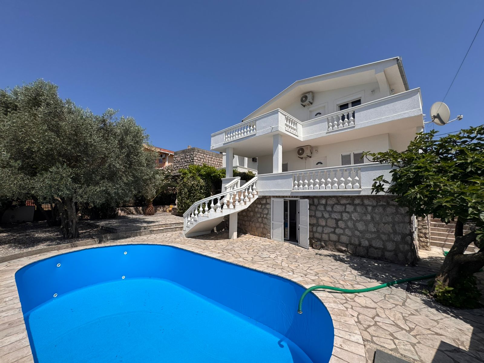 Elegant two-story white home with balconies, stone accents, pool & curved stairs—prime Ulcinj real estate by Ekosphere on montenegro-listings.me.