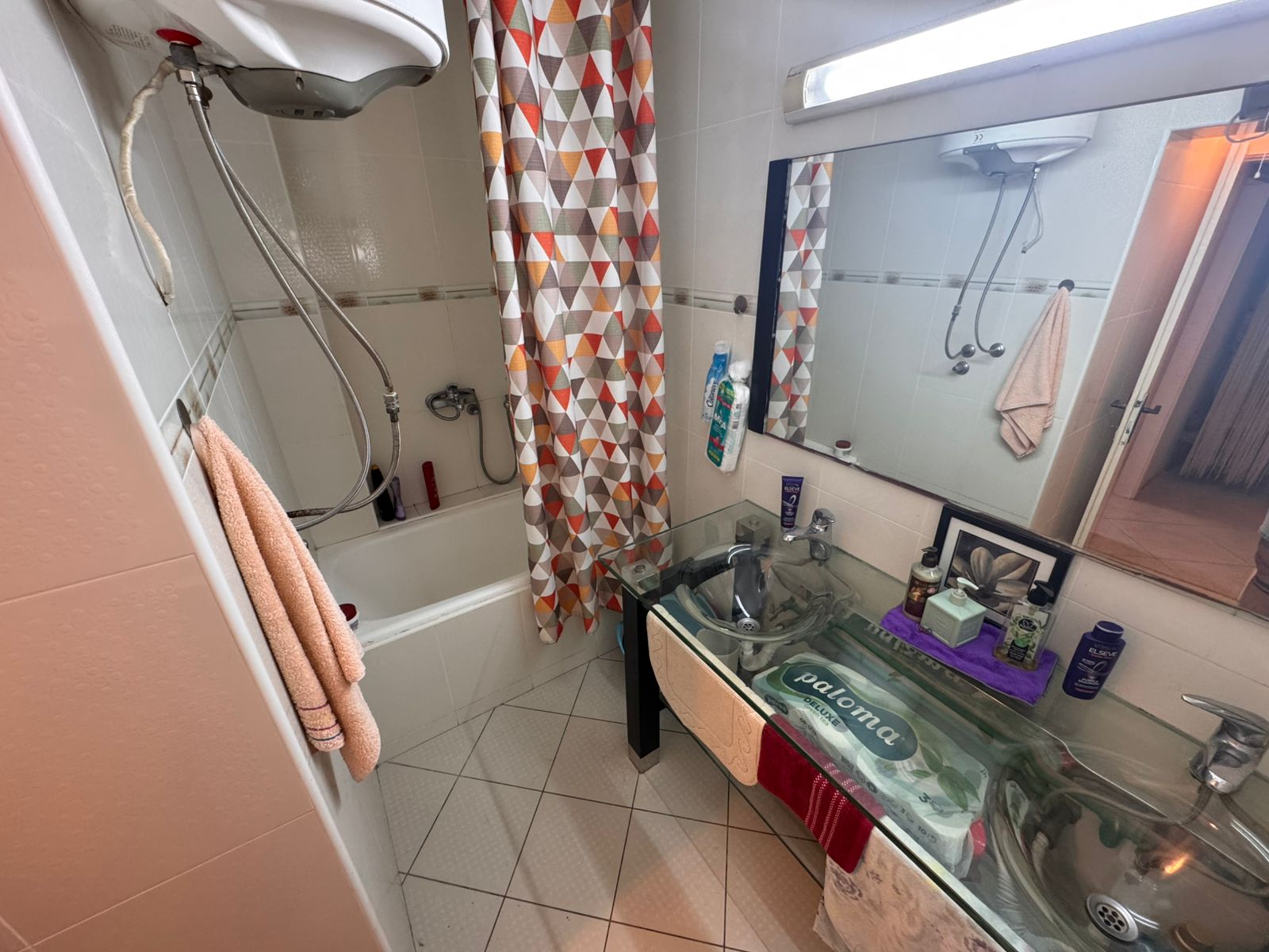 Modern Ulcinj bathroom with glass double sinks, tub, shower, plush towels; invest in Montenegro real estate with montenegro-listings.me.