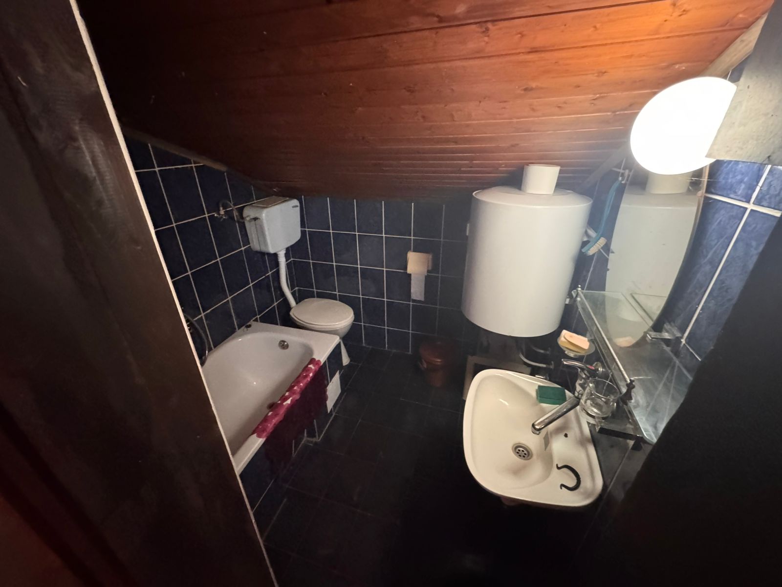 Modern bathroom in Ulcinj with blue tiles, wood-paneled ceiling, bathtub, and premium fixtures. Exclusive at montenegro-listings.me/Ekosphere.