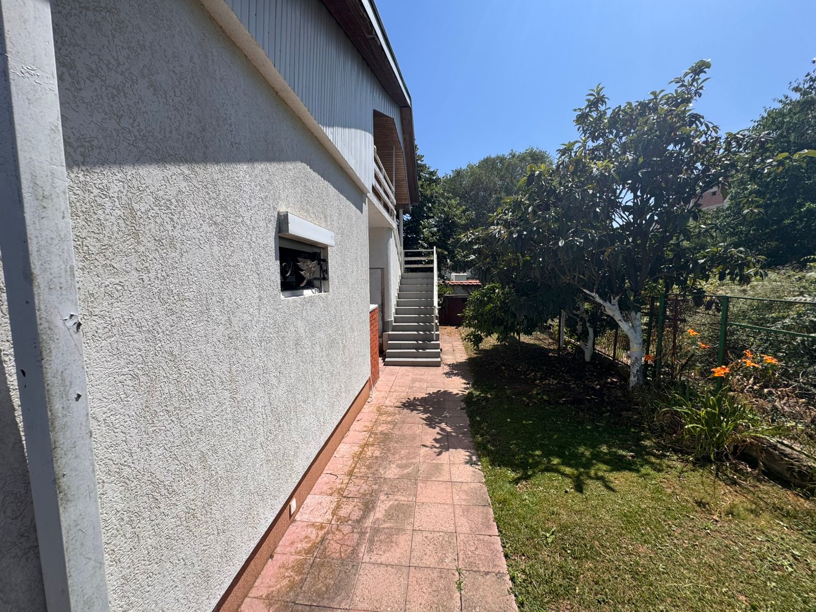 Stylish Ulcinj house with textured facade, lush garden, paved path, and stairs&mdash;ideal investment on montenegro-listings.me by ekosphere doo.