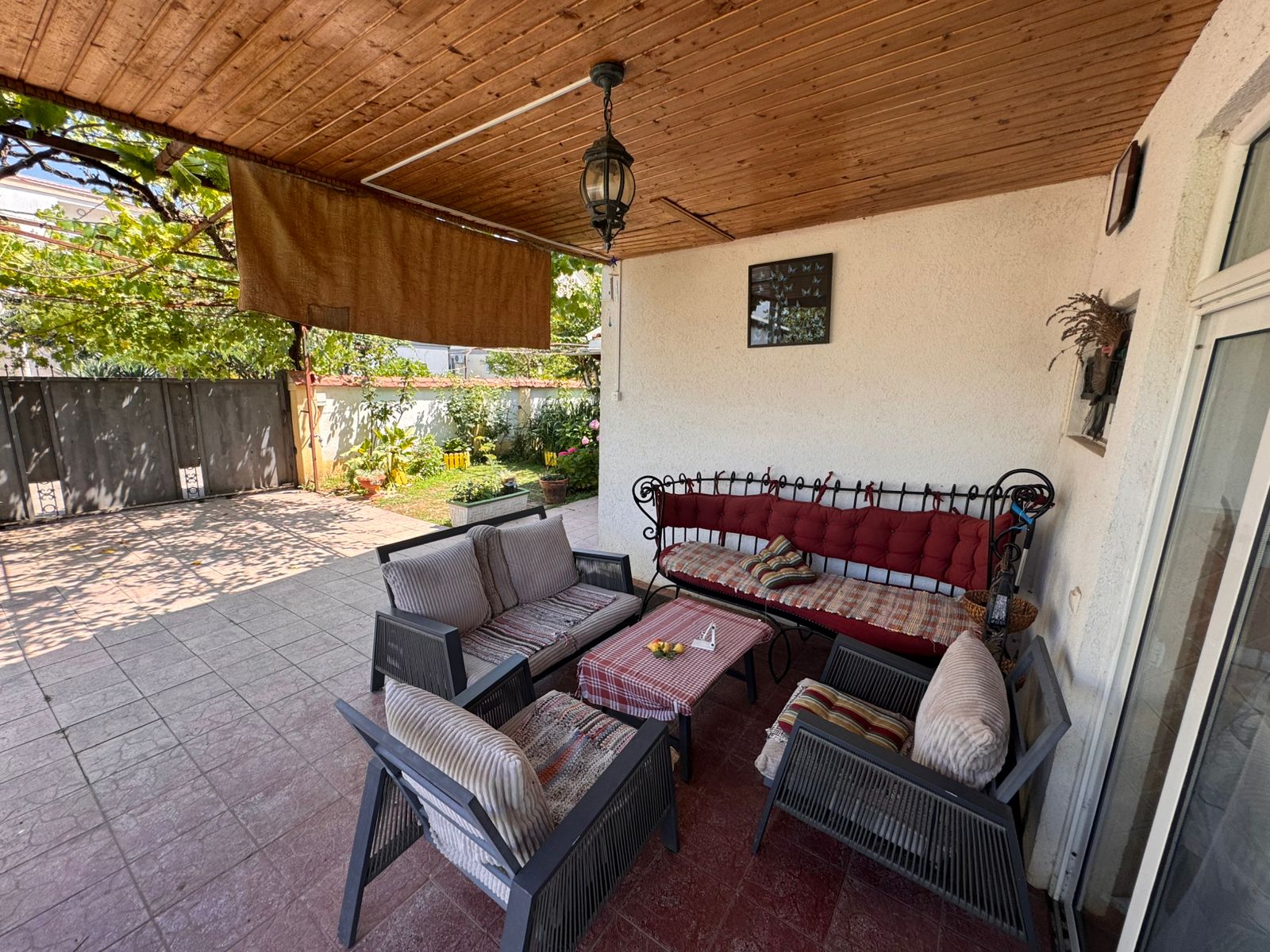 Spacious covered patio with cushioned seating, garden views, and stylish decor&mdash;prime Ulcinj Montenegro real estate by ekosphere doo.