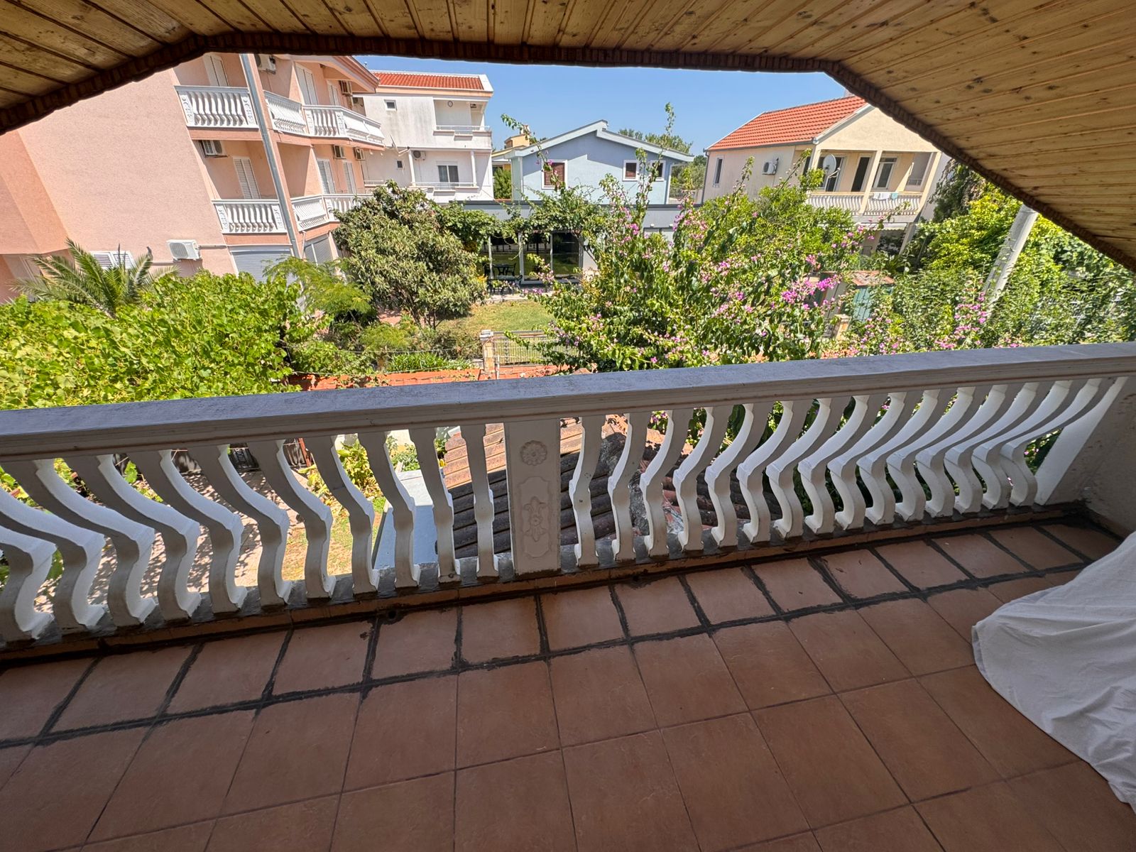 Spacious tiled balcony with white railing, garden view, and cityscape&mdash;prime Ulcinj property from montenegro-listings.me by ekosphere doo.