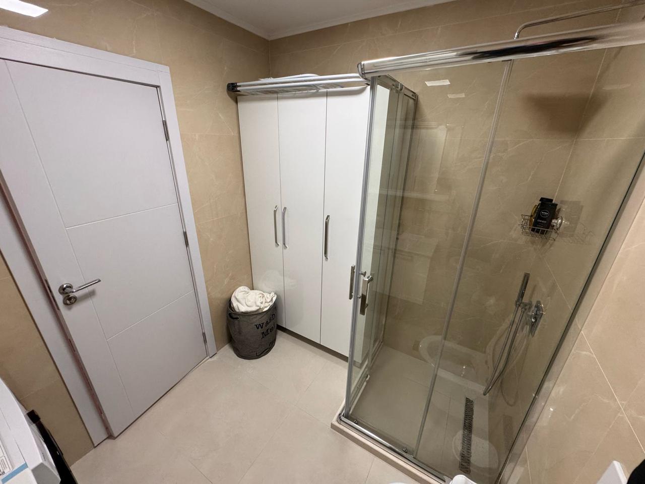 Elegant modern bathroom in Ulcinj, with beige tiles, glass shower, and storage; a premium investment by montenegro-listings.me/Ekosphere doo.