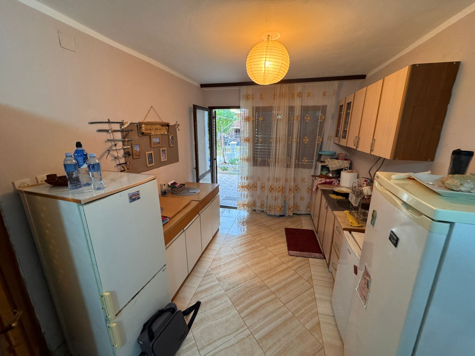 Modern compact kitchen in Ulcinj real estate, with white fridge, sleek cabinetry, bright lighting&mdash;offered by montenegro-listings.me.