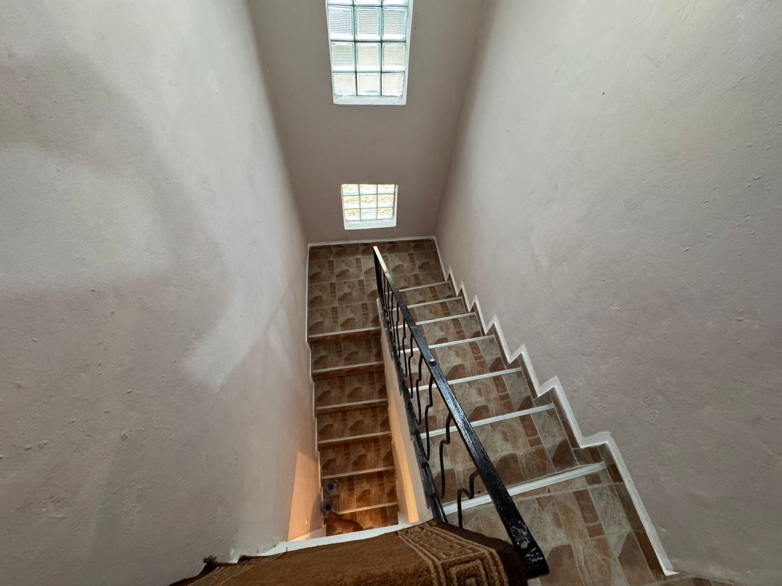 Modern staircase with brown tiles, black handrail, and skylights&mdash;bright, elegant Ulcinj real estate by ekosphere doo, montenegro-listings.me.