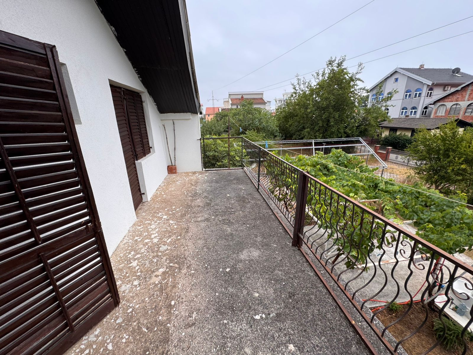 Modern concrete balcony with metal railing and lush garden views, prime Ulcinj property near amenities; listed on montenegro-listings.me.