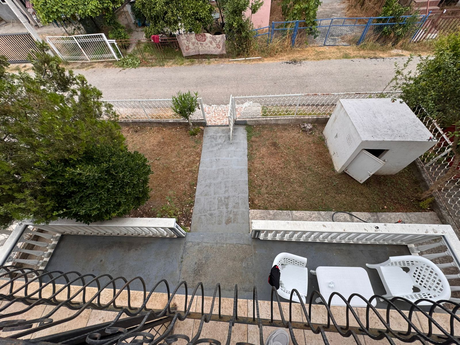 Upper balcony view in Ulcinj: private yard, stone path, white shed. Invest with montenegro-listings.me, a project of Ekosphere doo.