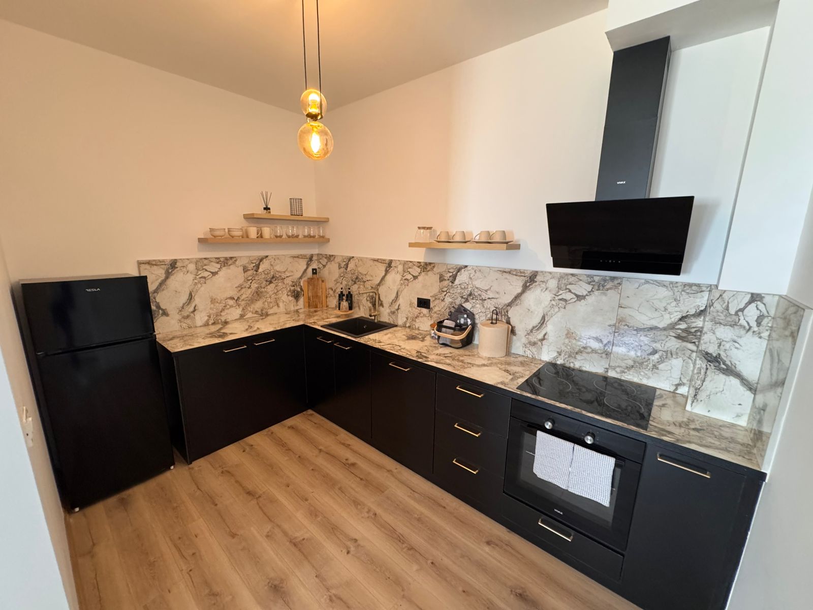 Sleek modern kitchen in Ulcinj, Montenegro: black cabinets, marble backsplash, induction cooktop&mdash;exclusive at montenegro-listings.me by Ekosphere Doo.