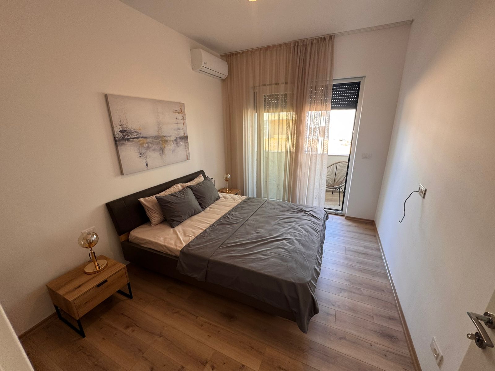 Stylish Ulcinj bedroom with gray bedding, wood accents, balcony & modern amenities; exclusive listing on montenegro-listings.me by ekosphere doo.