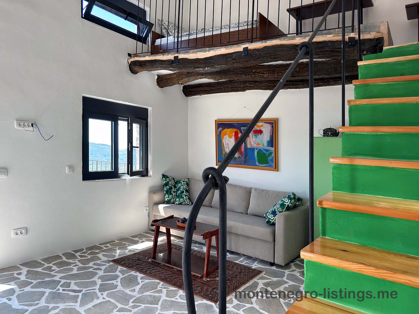 Ulcinj living room with gray sofa, vibrant cushions, wood table, green stairs. Exclusive Ekosphere property on montenegro-listings.me.