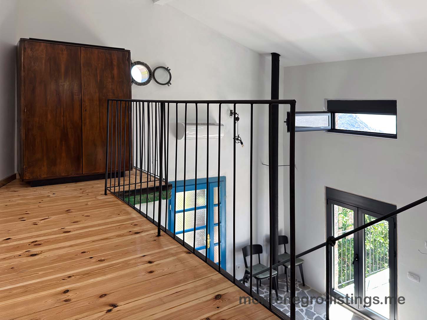 Elegant loft with wood floors, black metal railing, and large windows. Premier Ulcinj property listed by montenegro-listings.me (ekosphere doo).