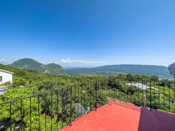 Listings for Sale - Stunning red terrace with black metal railing, panoramic green hills, and mountain views—prime real estate in Ulcinj, Montenegro.