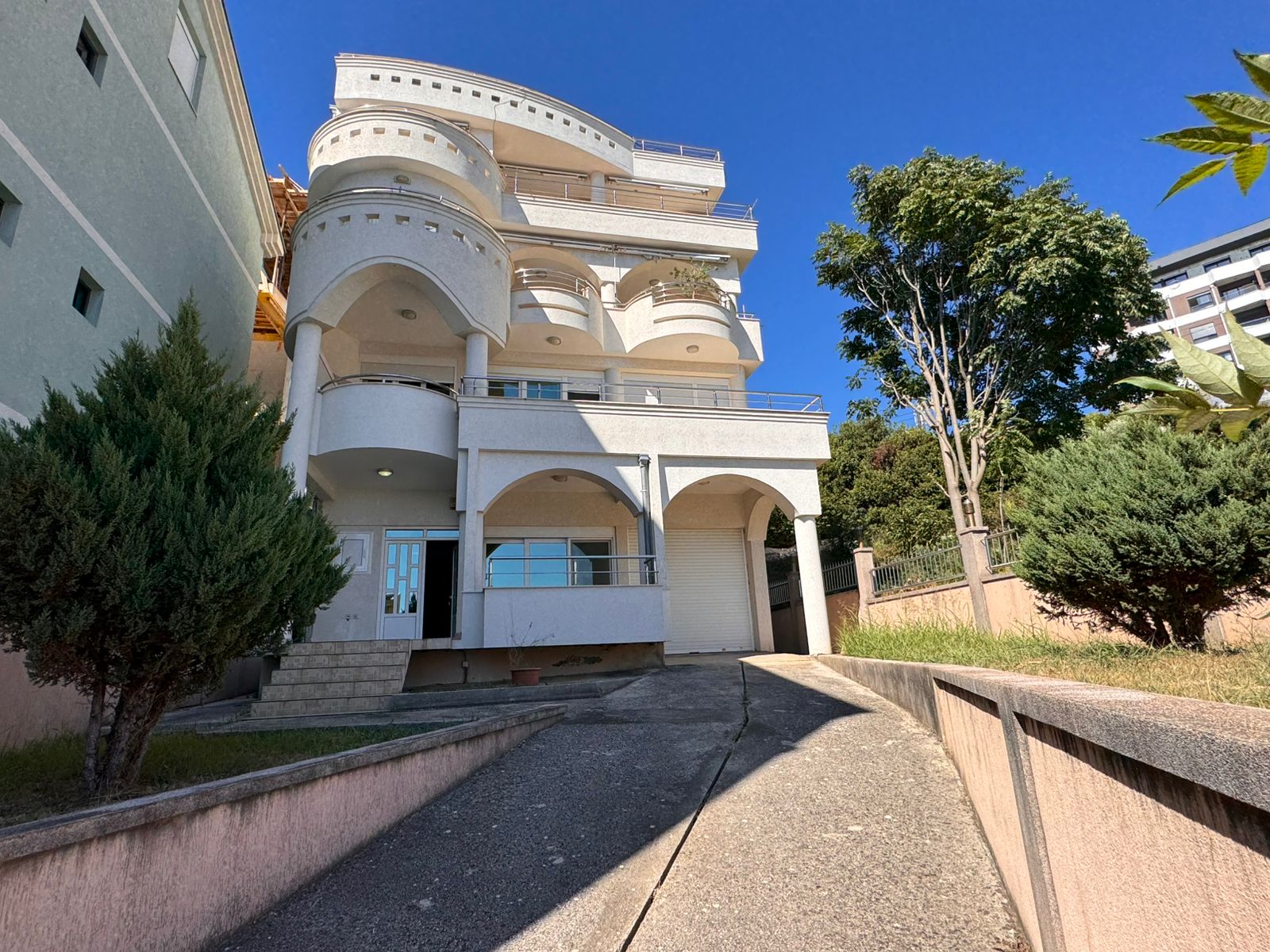Elegante dreistöckige weiße Villa in Ulcinj, mit gewölbten Balkonen, privater Auffahrt, üppigen Bäumen. Exklusiv auf montenegro-listings.me von ekosphere doo.