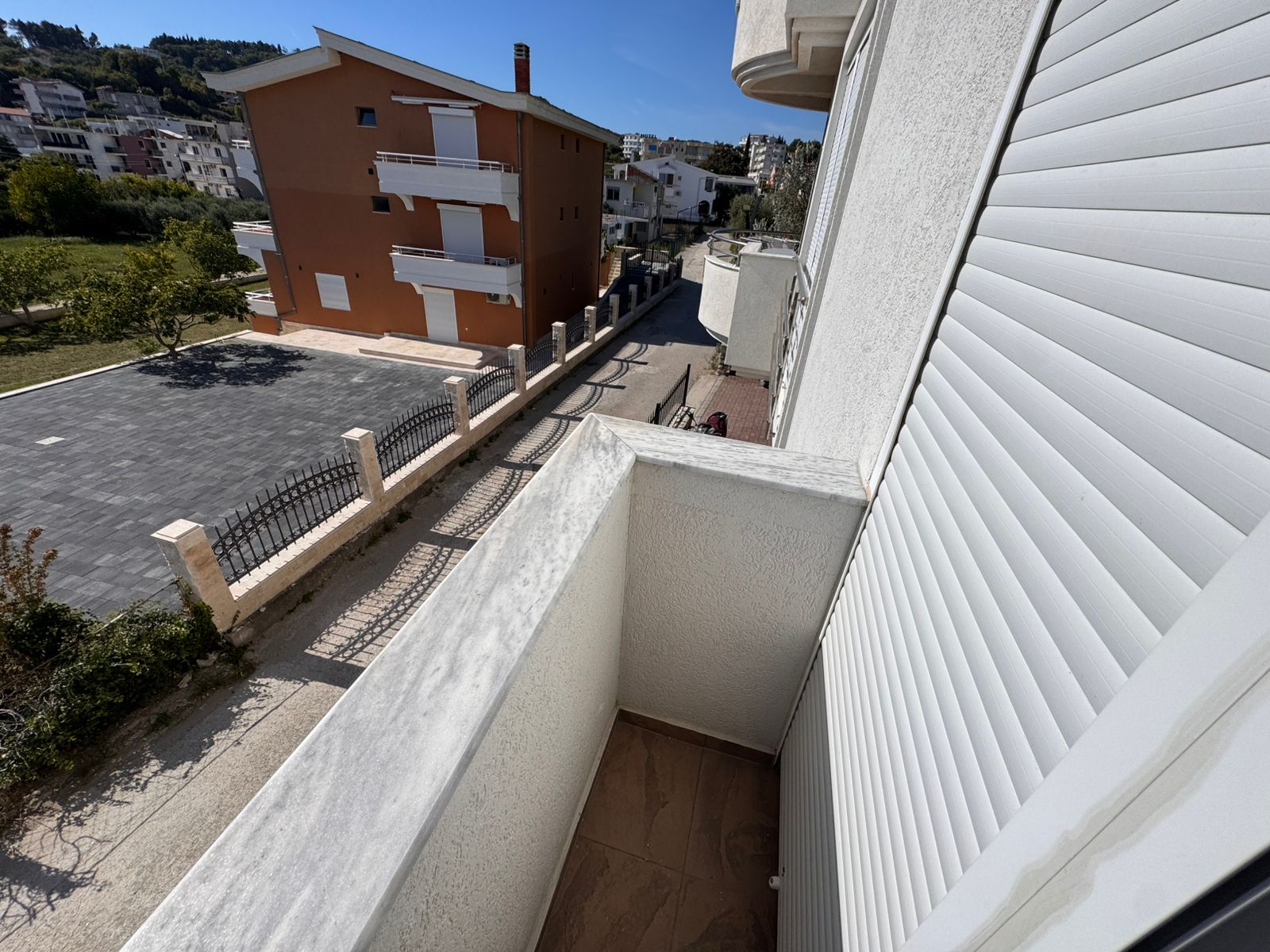 Stunning marble-railed balcony view over a serene Ulcinj street, lush greenery, quality apartments&mdash;exclusive at montenegro-listings.me by ekosphere doo.