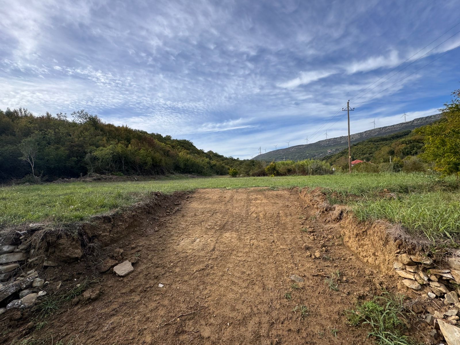 Scenic Ulcinj land with lush greenery, hills, and wind turbines&mdash;prime real estate investment via montenegro-listings.me by ekosphere doo.