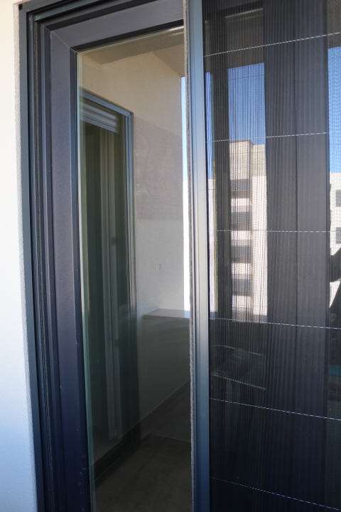 Modern sliding glass door with mesh screen opens to balcony; enjoy Ulcinj views. Exclusive via montenegro-listings.me by ekosphere doo.