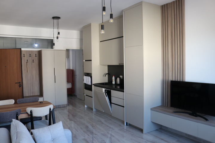 Modern Ulcinj apartment: light cabinetry, built-ins, designer lighting, wall TV, dining set, gray sofa. Exclusive at montenegro-listings.me by ekosphere doo.