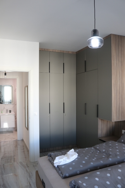 Elegant Ulcinj bedroom with sleek gray wardrobes, stylish polka dot bedding, ensuite bath—ideal Montenegro property investment.