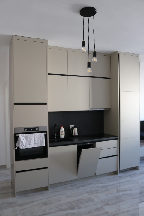 Sleek modern kitchen in Ulcinj, Montenegro: beige cabinets, black counters, oven, open dishwasher. Listed on montenegro-listings.me by ekosphere doo.