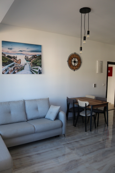 Elegant Ulcinj apartment: modern living room, gray sofa, marble floors, dining area. Invest at montenegro-listings.me by ekosphere doo.