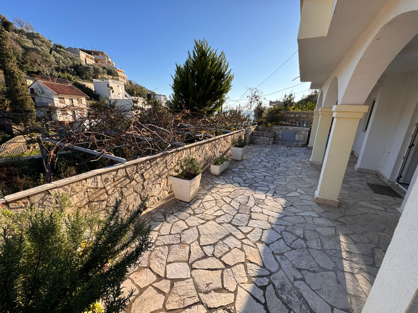 Elegant stone terrace with potted plants, arches, and scenic Ulcinj views. Prime investment via montenegro-listings.me by ekosphere doo.
