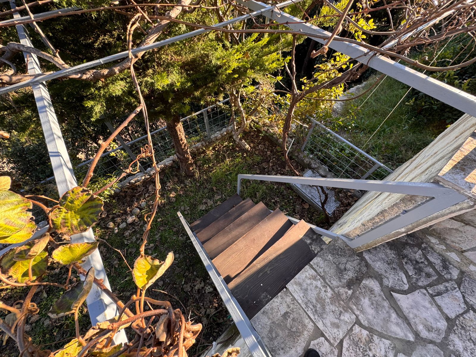 Elegant outdoor wooden stairs with sleek metal railings, lush greenery, and secure fencing&mdash;prime Ulcinj investment via montenegro-listings.me by ekosphere doo.