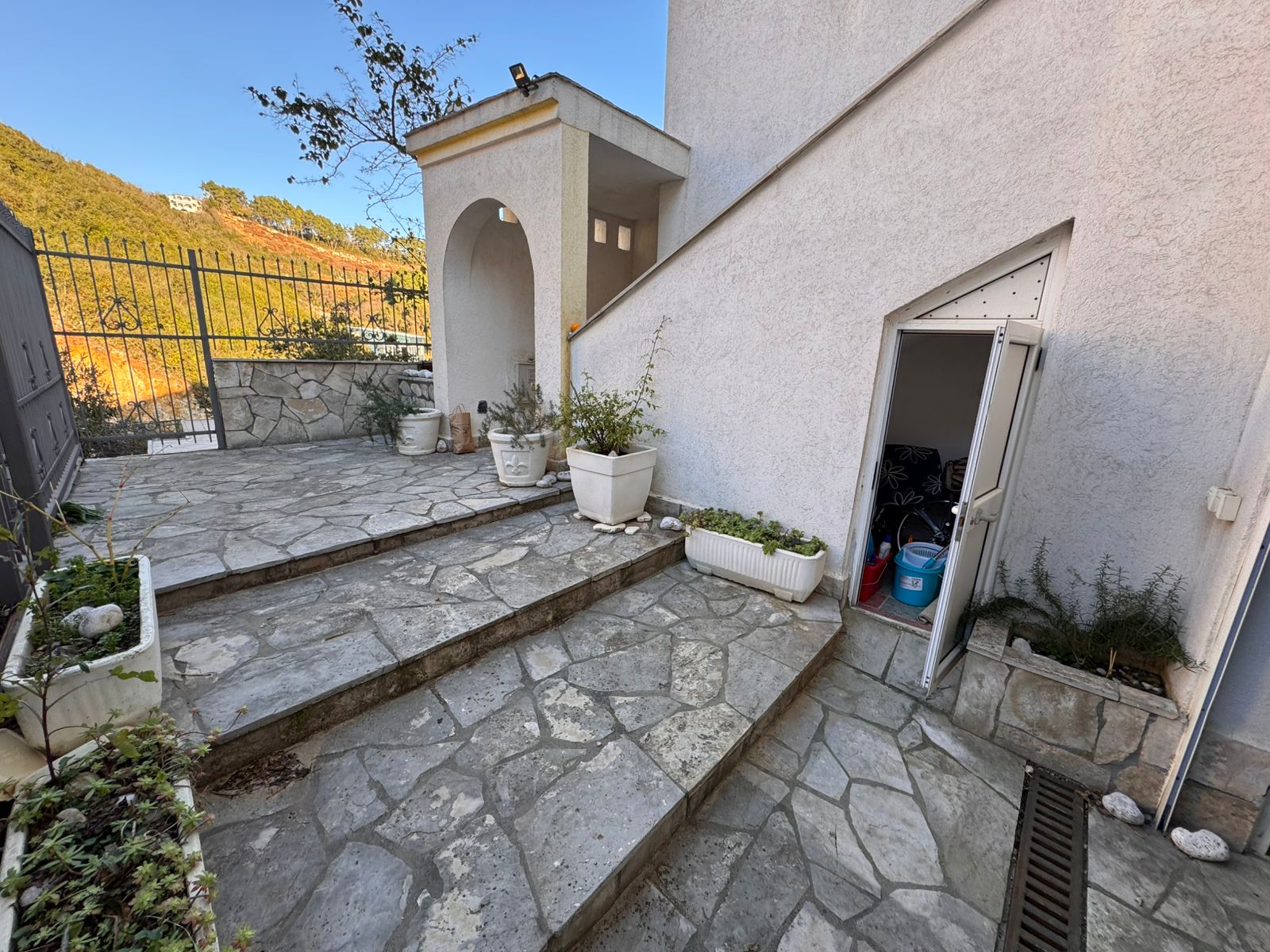 Elegant stone-paved terrace with landscaped planters, steps to a white Ulcinj home. Exclusive Montenegro investment by ekosphere doo.