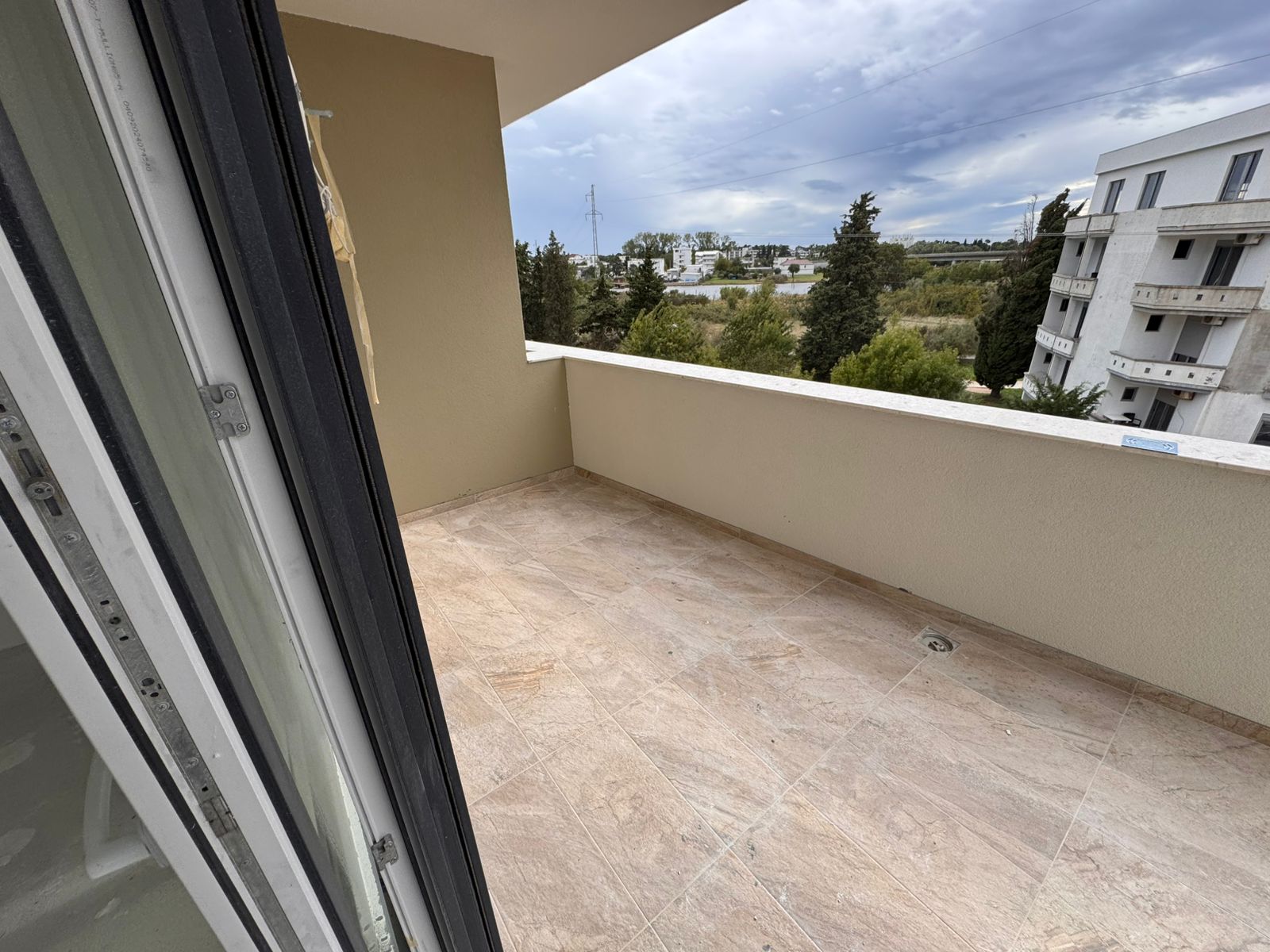 Spacious tiled balcony with beige walls, open views to greenery and nearby apartments&mdash;prime Ulcinj real estate by montenegro-listings.me.