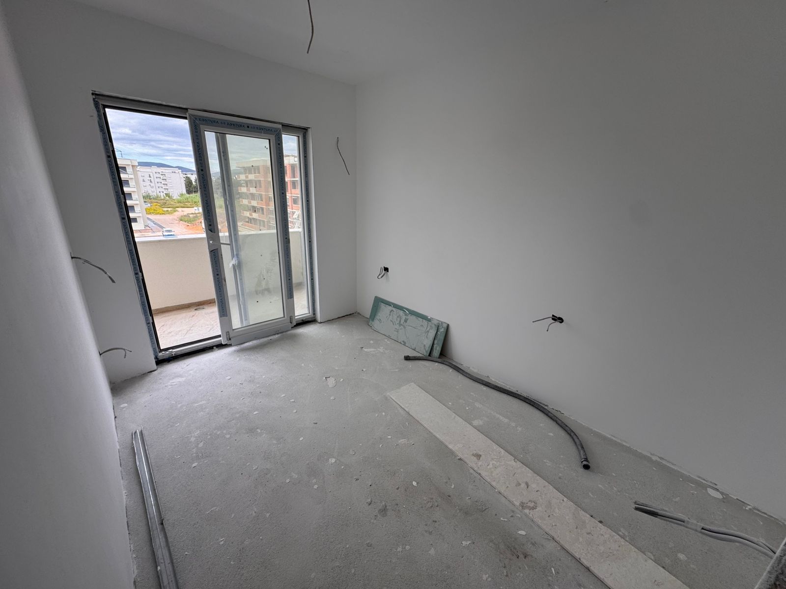 Spacious unfinished apartment in Ulcinj with white walls, large glass balcony door, and investment potential&mdash;exclusive to montenegro-listings.me.
